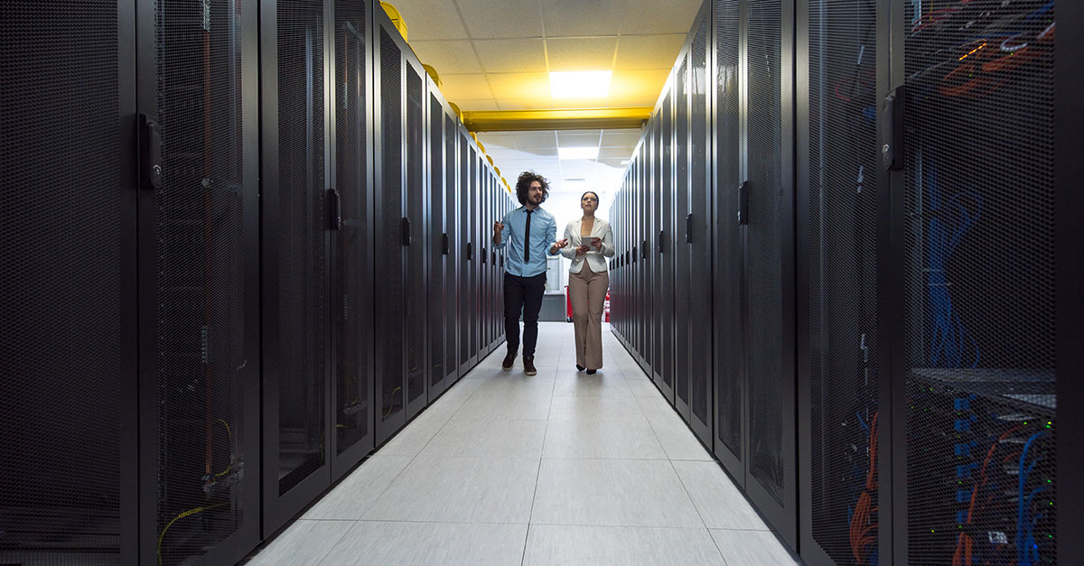 Two people walking and talking in a data center. 