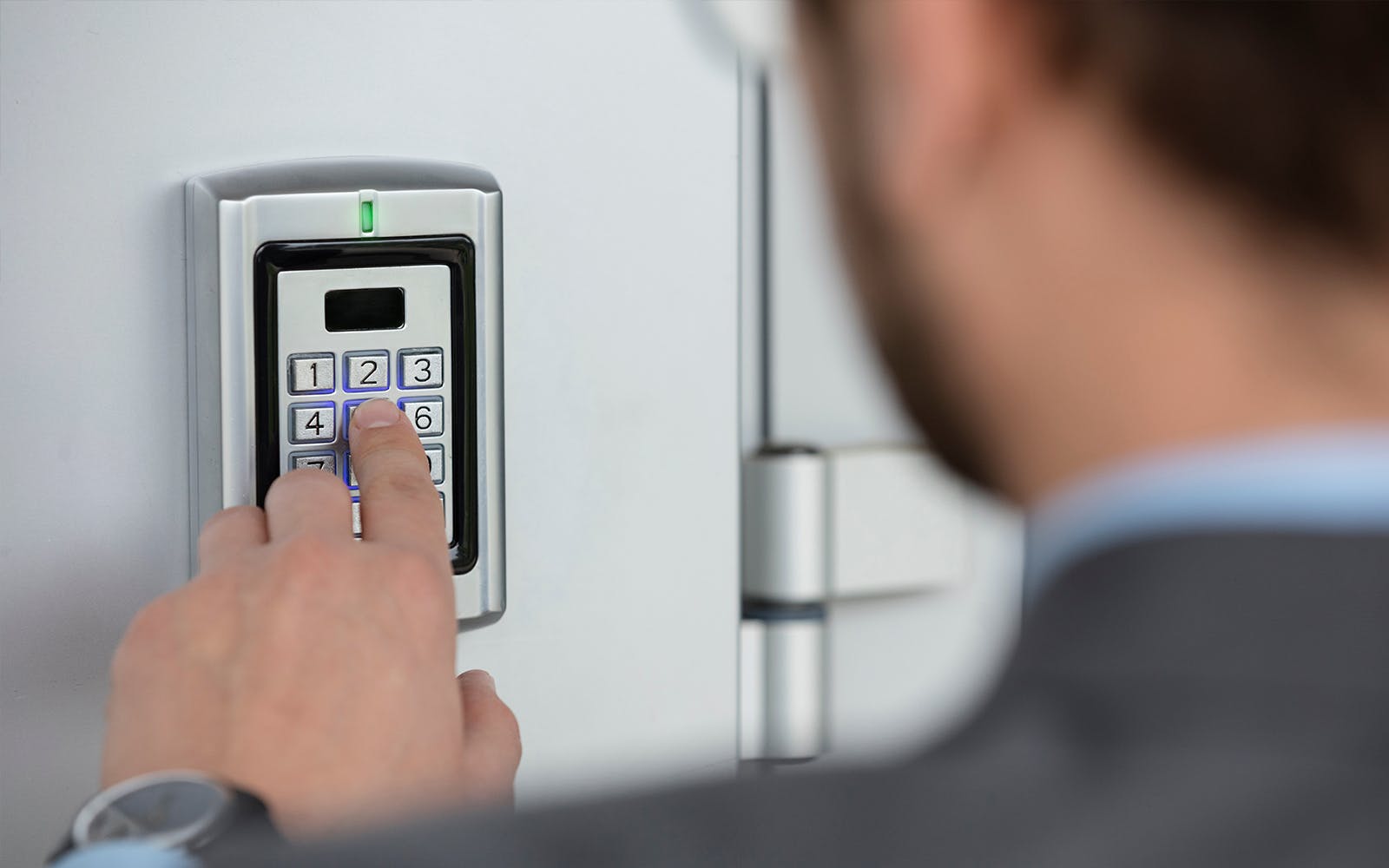 Man entering PIN code outside of building to enter