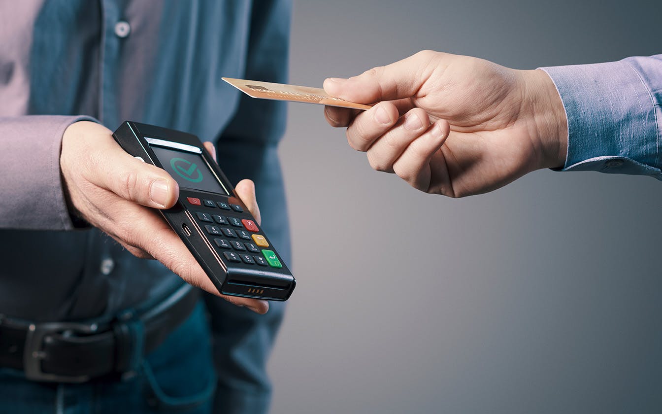 A man using his credit card to complete a contactless transaction 