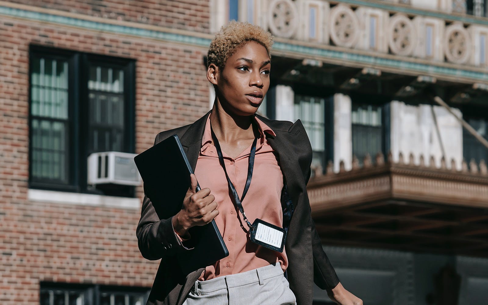 Woman in pink shirt and black jacket with an access card on a lanyard around her neck.
