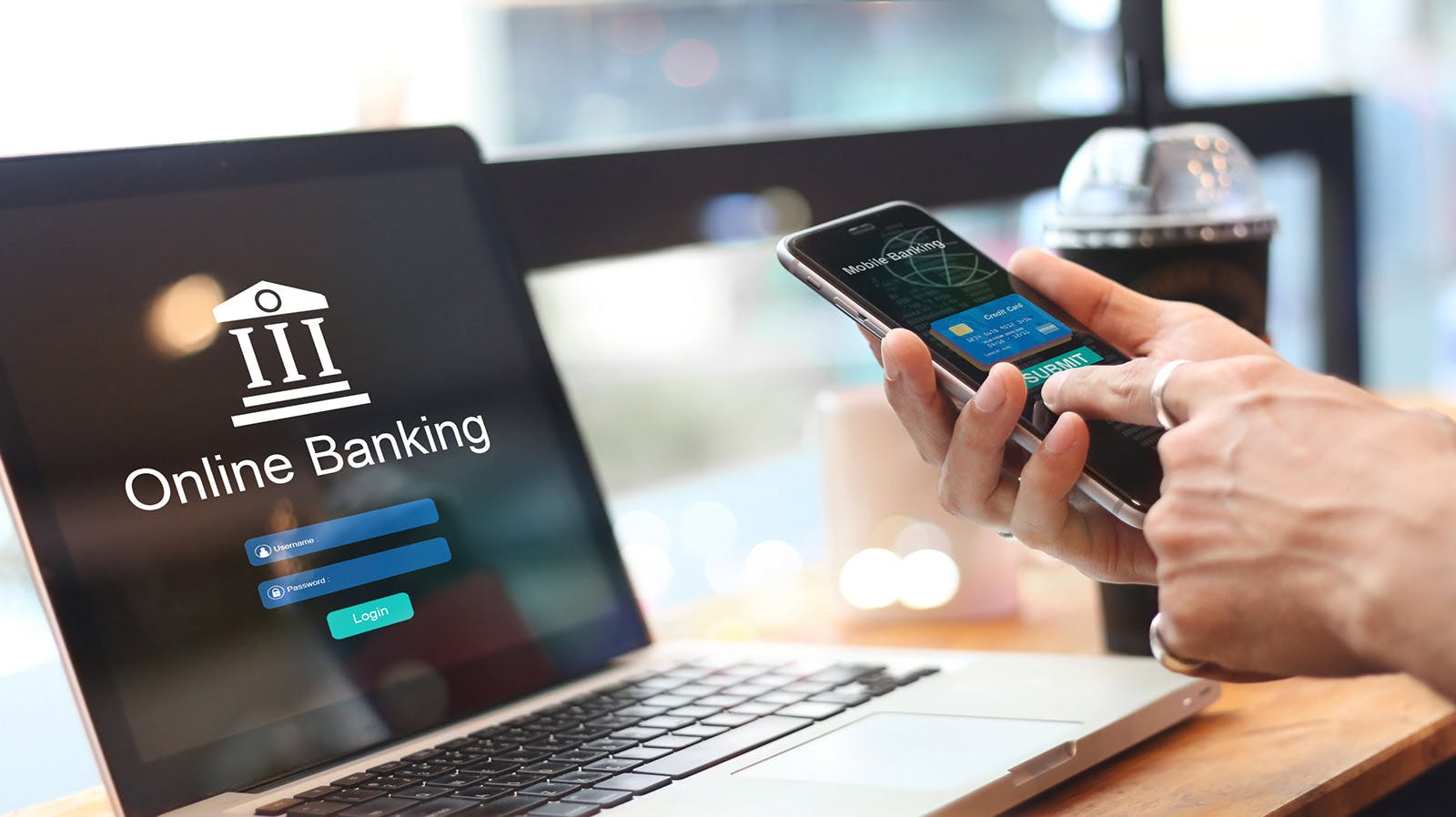A person using phone and laptop to access online banking