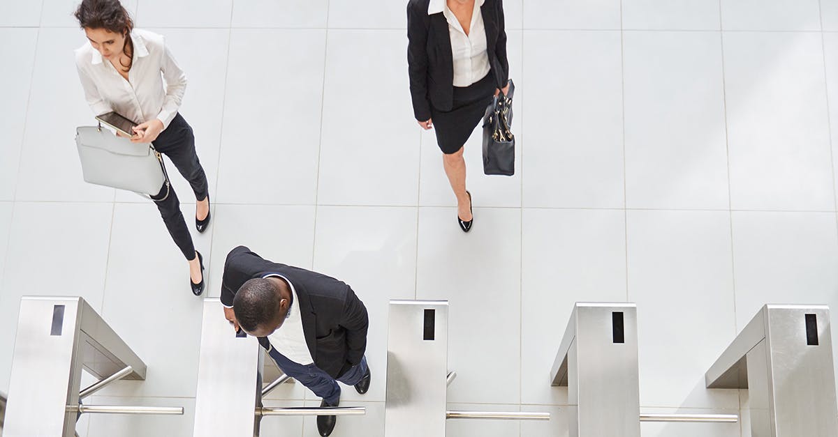 People in corporate building walking through turnstiles. 