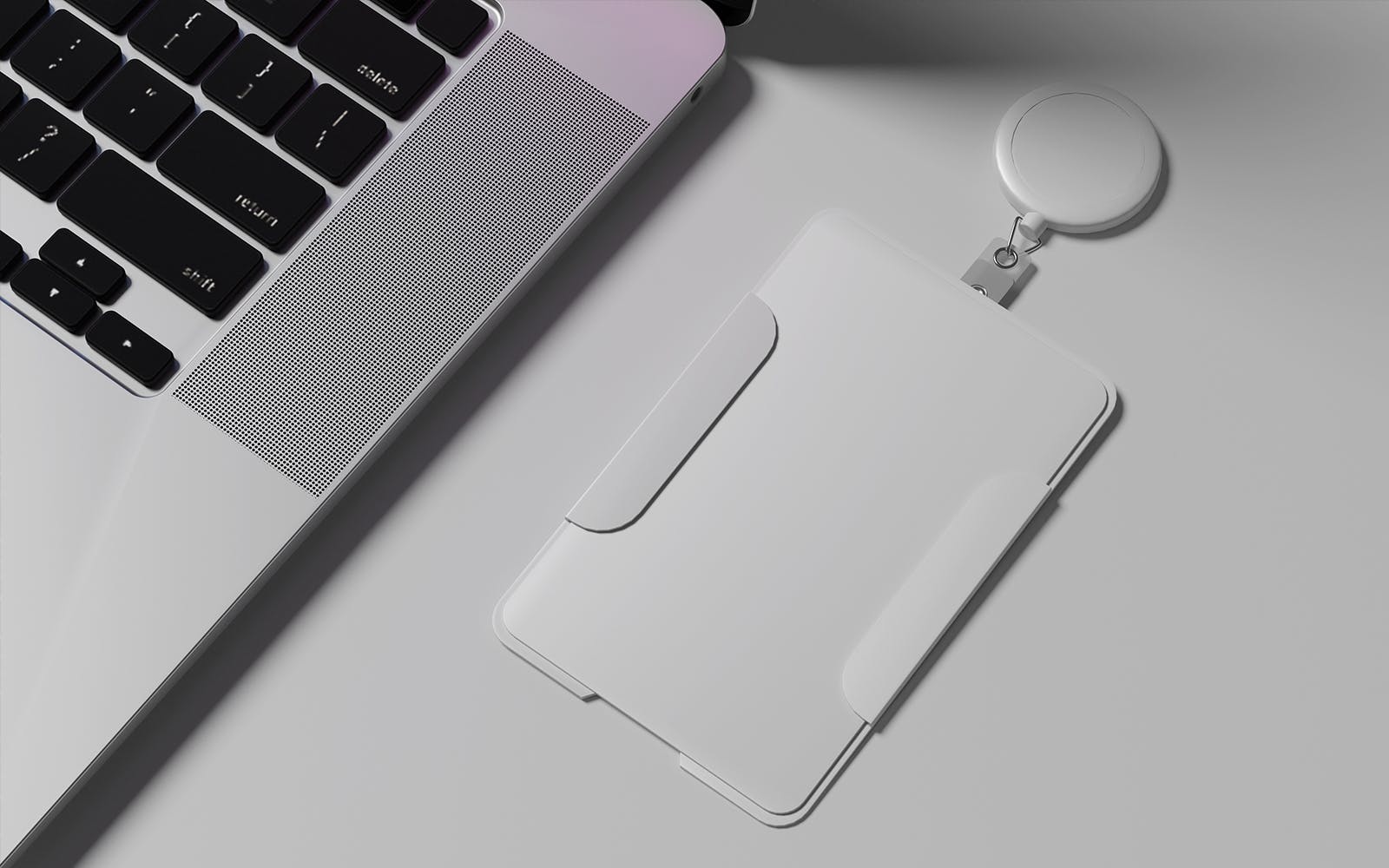 White proximity access badge sitting on a desk next to a laptop